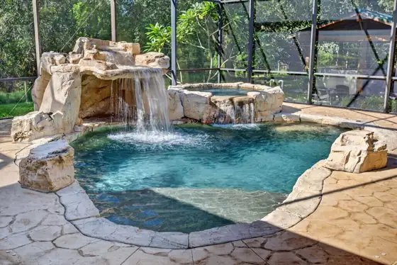 Gas-heated PebbleTec pool with natural-stone grotto and waterfall